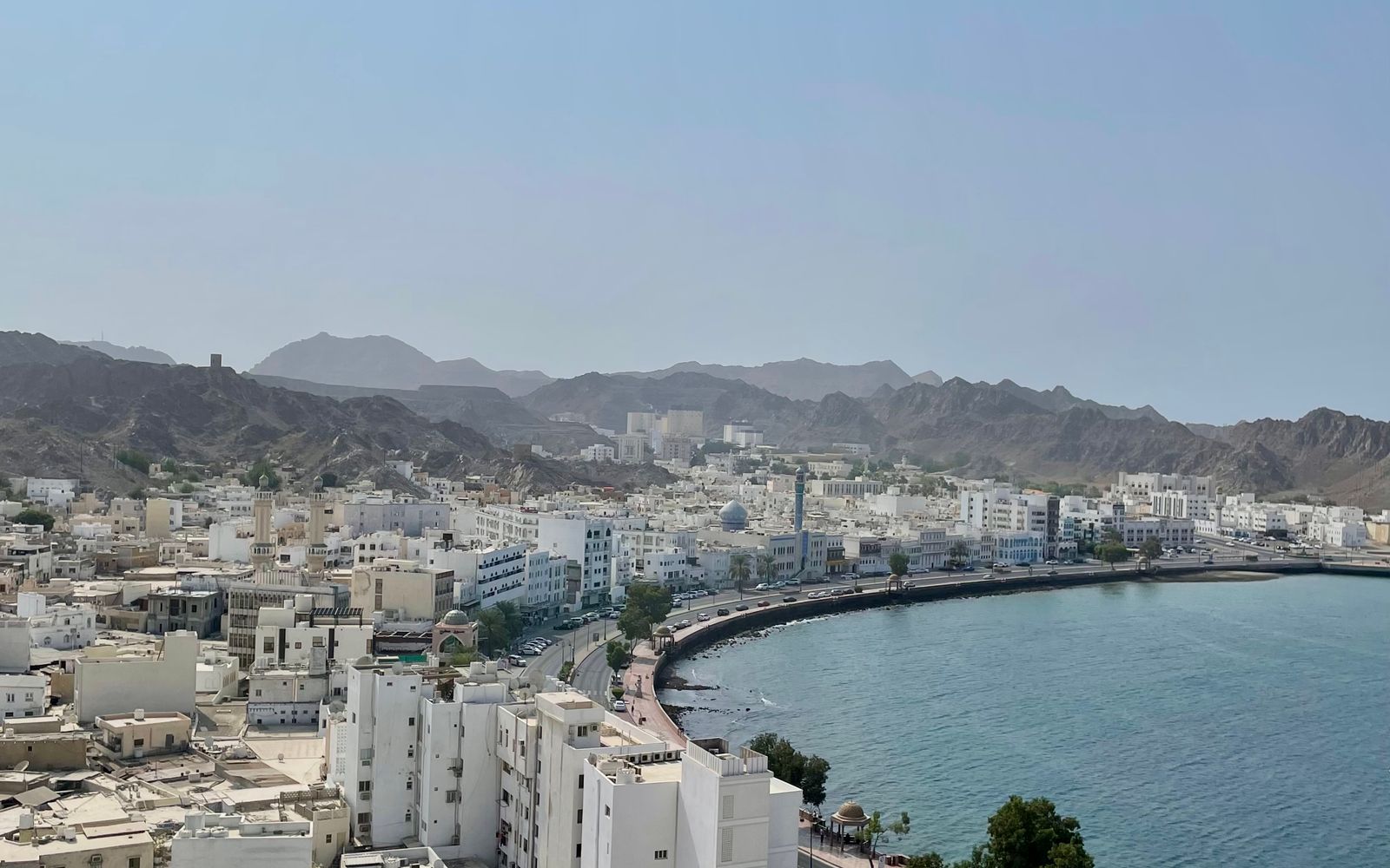 Aerial view of Muscat's coastline framed by rugged mountains, Oman